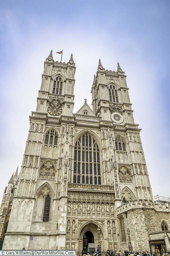 The facade of Westminster Abbey dominated by it's two white towers and large stained glass window.