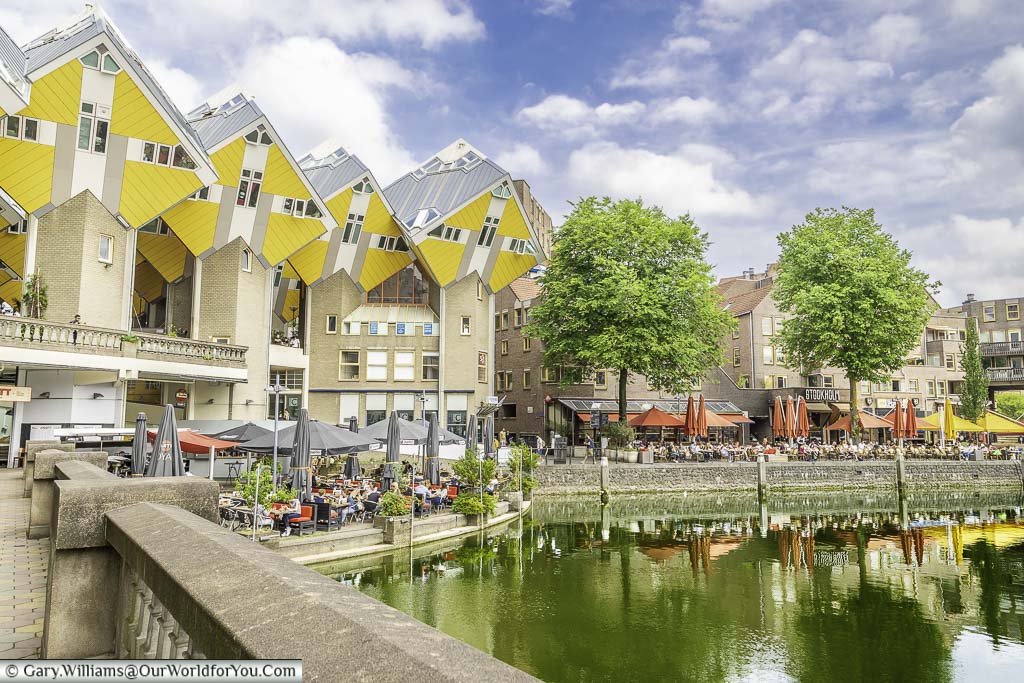 The iconic bright yellow cube houses overlooking patrons filling the harbourside cafes, bars and restaurants in Rotterdam, Holland
