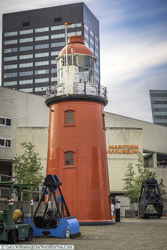 The bright red lighthouse against rotterdam's skyline at the harbourside maritime museum