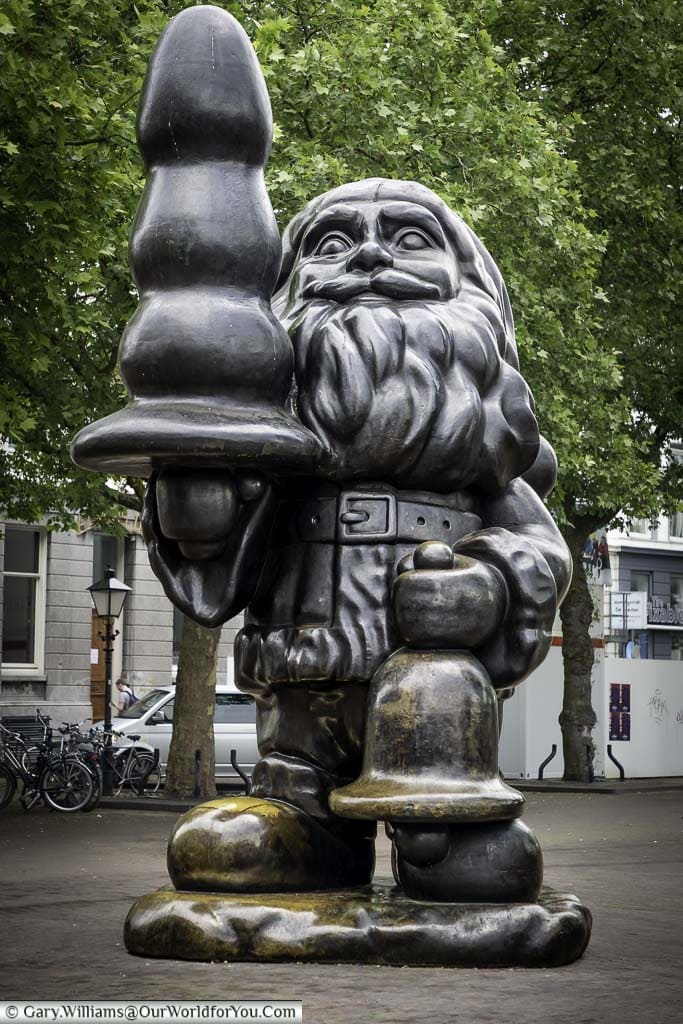 A larger than life brass Santa statue in Rotterdam holding an object that could represent a Christmas tree, but in reality, it's a sex toy.
