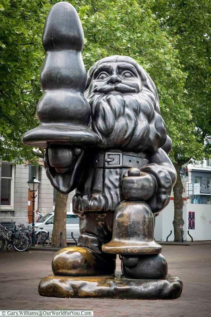 A larger than life brass Santa statue in Rotterdam holding an object that could represent a Christmas tree, but in reality, it's a sex toy.