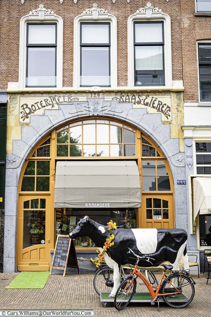 A full-size plastic cow outside an art deco cheese shop in rotterdam's cool district