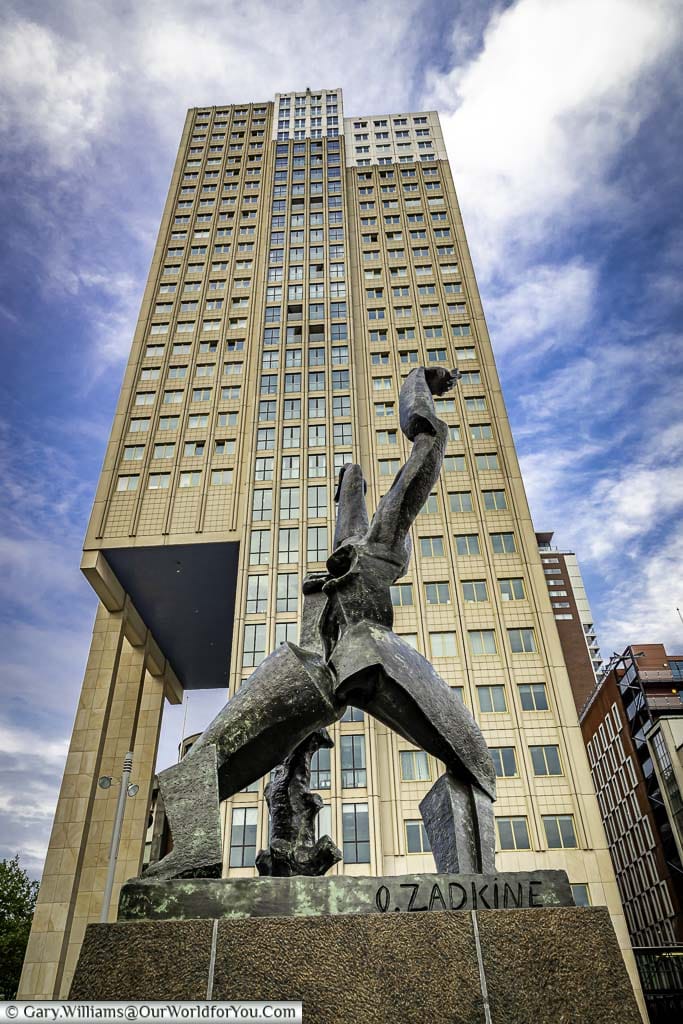 The abstract bronze 'Destroyed City monument' against the backdrop of a stylish 1960s skyscraper in rotterdam