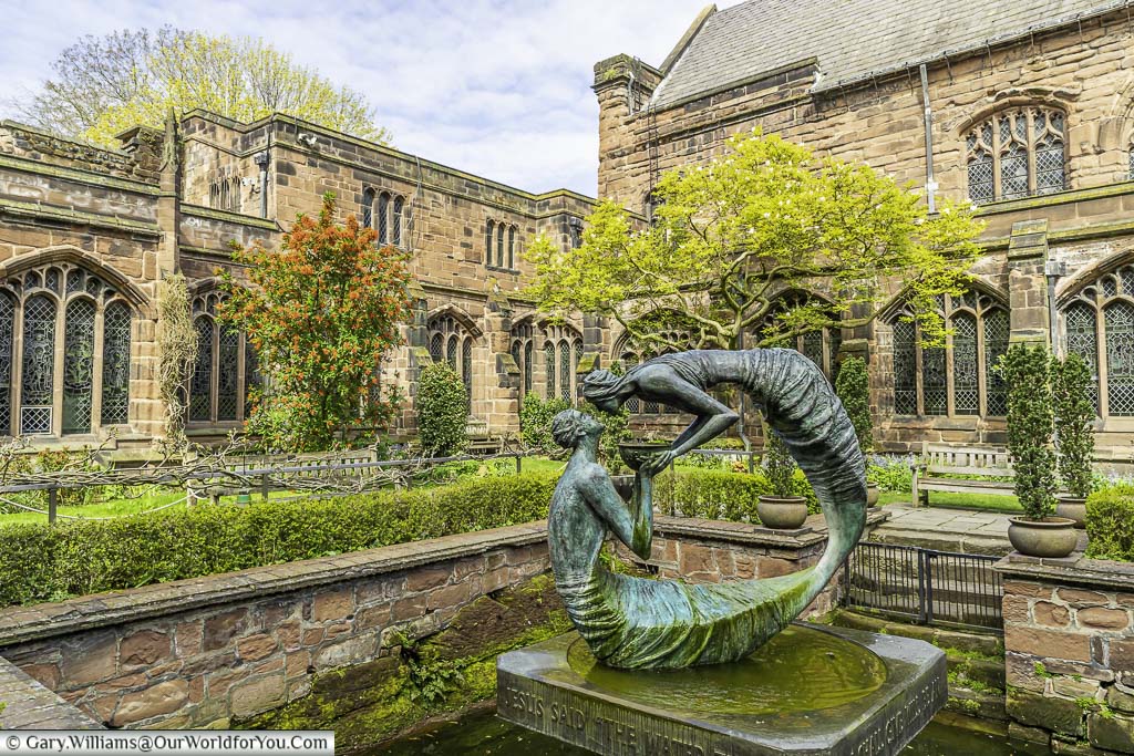 The cloisters garden ,featuring a bronze statue in the centre of a pond, in chester cathedral