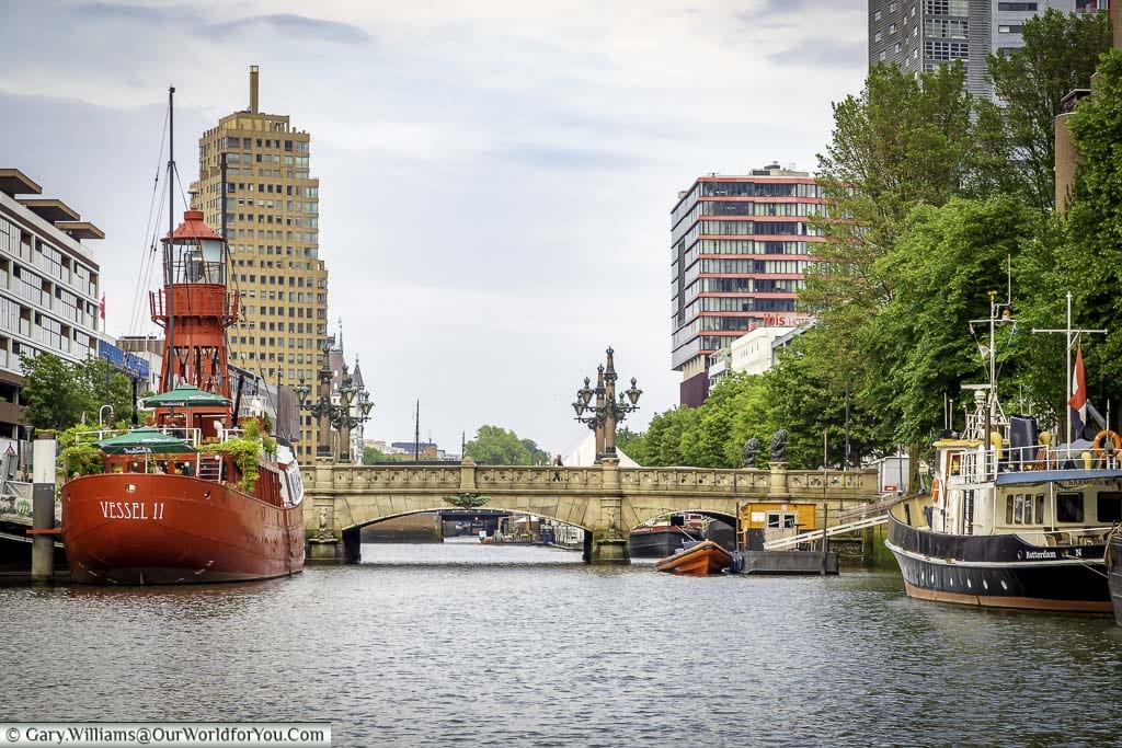 A Lighthouse boat and other smaller craft moored up in rotterdam's waterways in front of the Regentessebrug bridge
