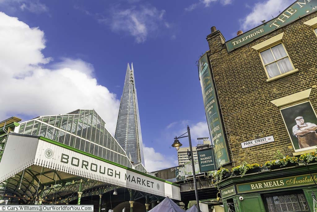 One entrance to london's borough market next the the market porter pub and the shard in the background