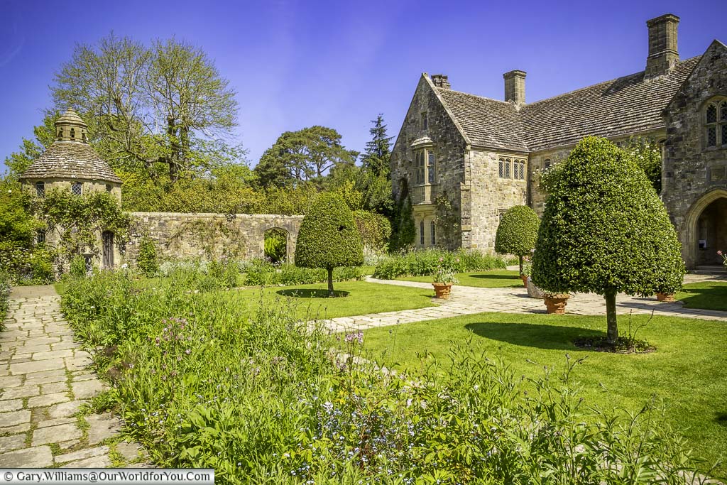 The beautiful manicured formal forecourt garden with the stone dovecote in the corner next to nyman's house