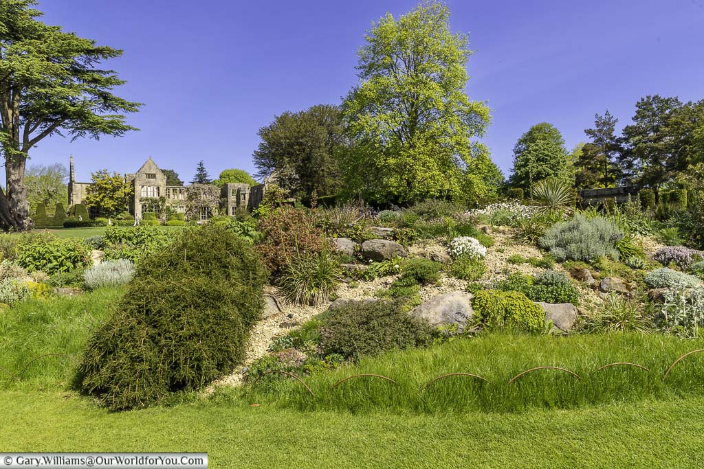 Another view from the rockery of the ruined national trust nymans house on a bright day under a blue sky