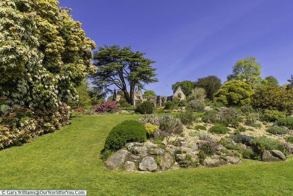 A view from the rockery of the ruined national trust nymans house on a bright day under a blue sky