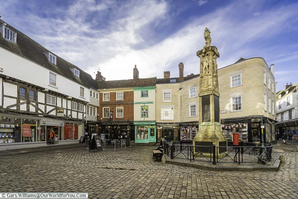 The cobbled pedestrian Buttermarket area of Canterbury, with the war memorial in the centre.