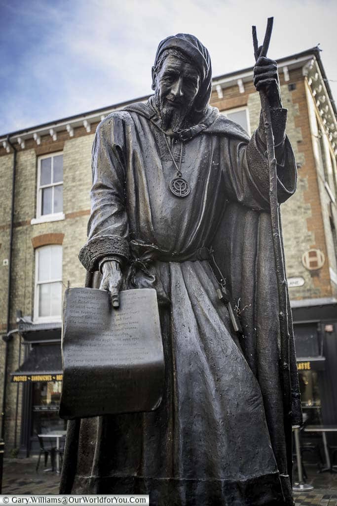 A statue to Geoffrey Chaucer, dressed as a pilgrim, sharing his Canterbury Tales, in the High Street of Canterbury, Kent.