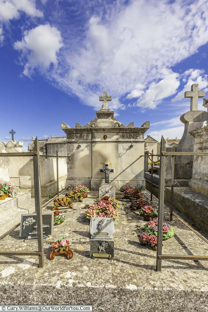 A large stone grave plot, decorated with porcelain floral tributes in the cemetery of Saint-Rémy-de-Provence, France