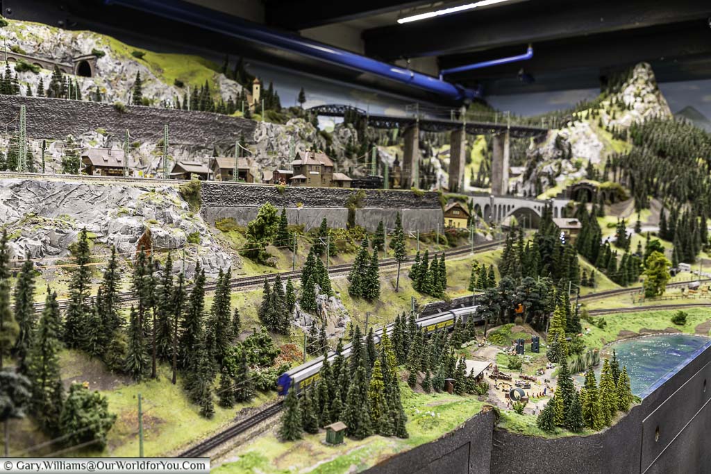 A multi-level model railway scene leading from the mountains to the lake's edge in miniatur wunderland, hamburg, germany