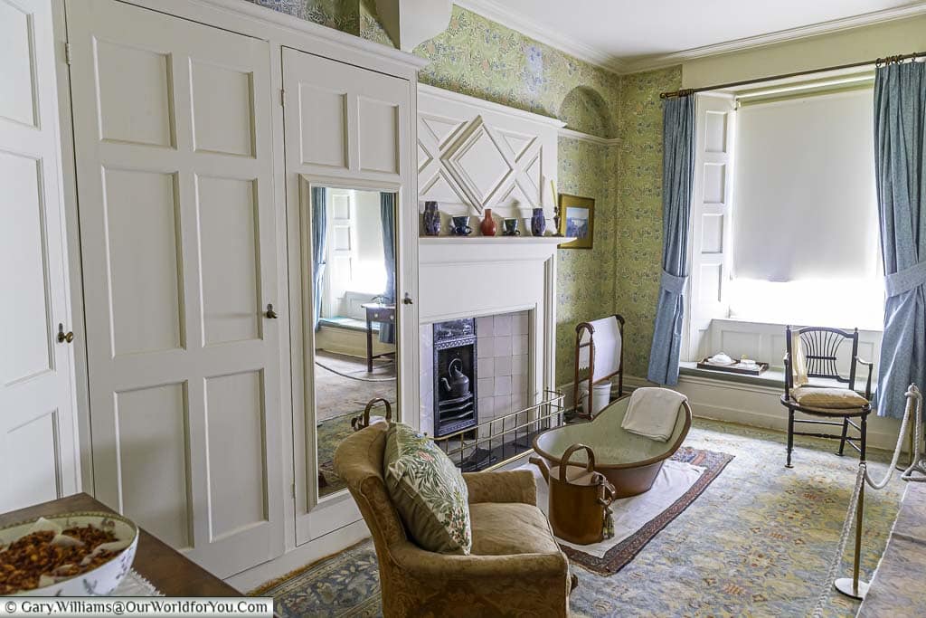 The white painted wooden wardrobes in the arts and crafts styled larkspur room complete with a standalone bath in front of the open hearth fireplace at the national trust's Standen house and garden