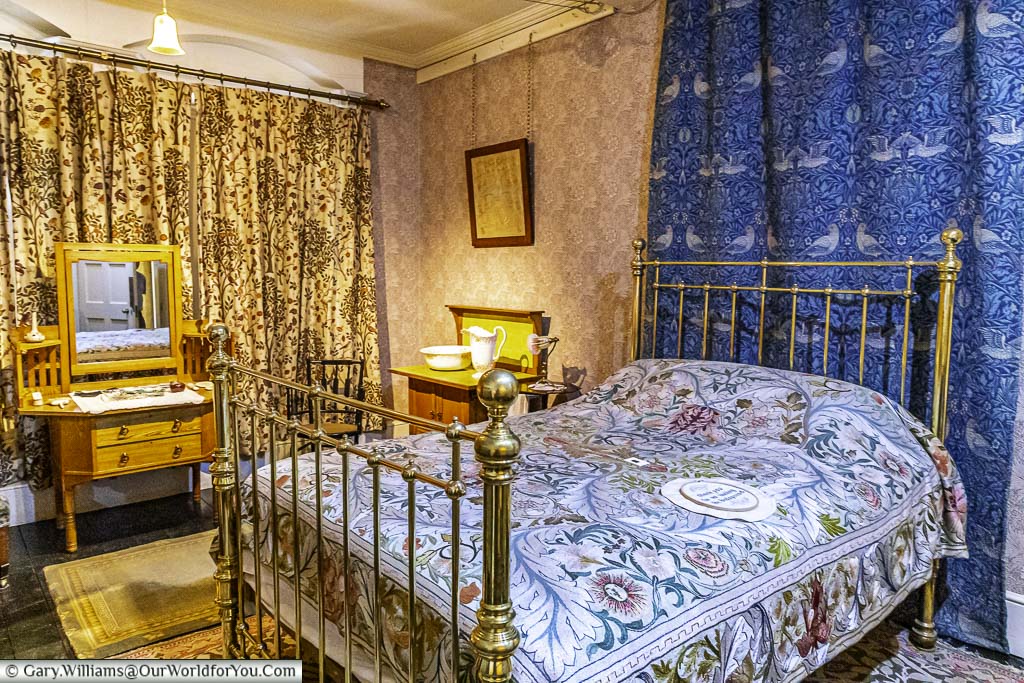 A arts and crafts period brass bed in the centre of a well-decorated tidy bedroom