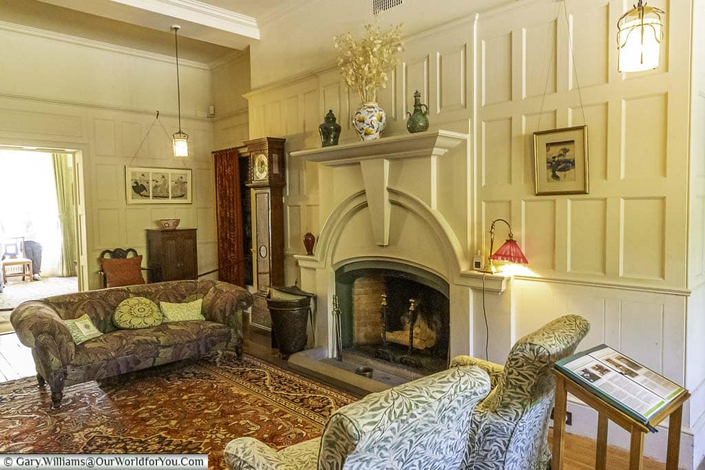 the reception room at standen house is decorated in the arts and crafts style, with white wood panelled walls and a fireplace