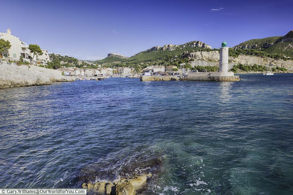 The entrance to the harbour at Cassis protected by a lighthouse, with the provencal town, in the background.