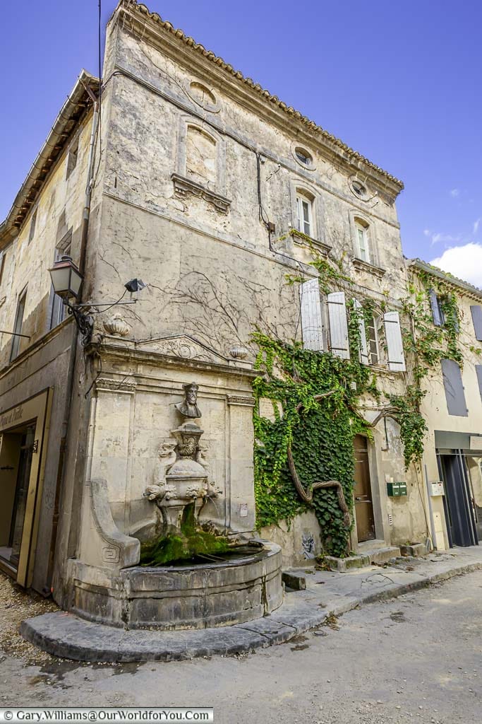 A stone fountain built into the corner of a building in the quiet lanes of Saint-Rémy-de-Provence, France