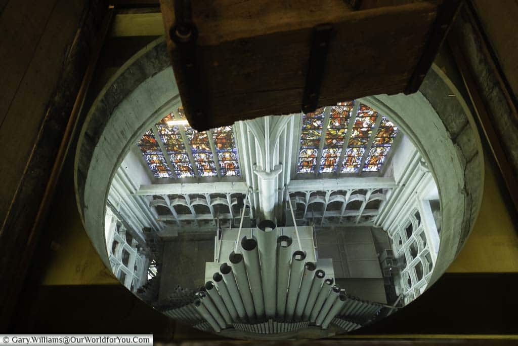 The view down from the crane chamber to the pipes of St Rumbold's Cathedral's organ below and the stained glass window behind.