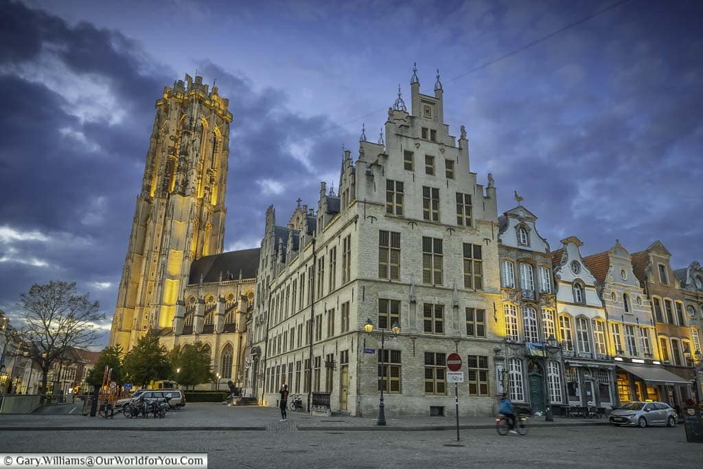 The illuminated tower of St Rumbold’s Cathedral at dusk as seen from the grote market in mechelen, flanders