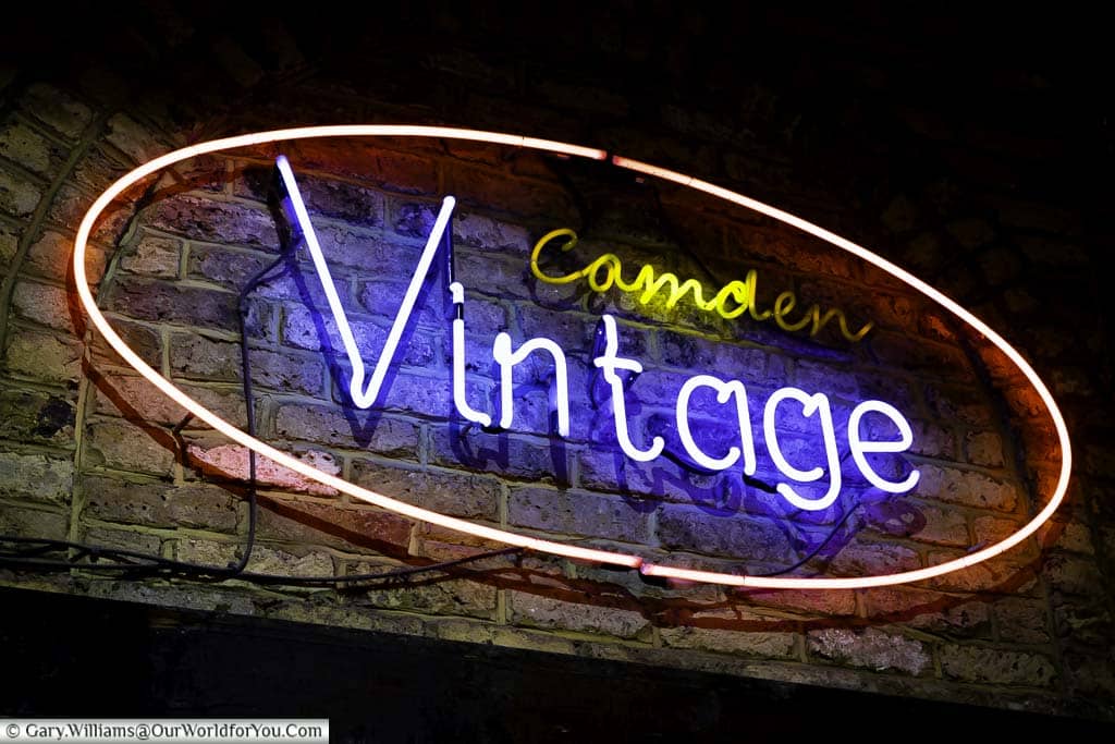 A neon sign for Camden Vintage mounted directly on the brickwork in Camden Market.