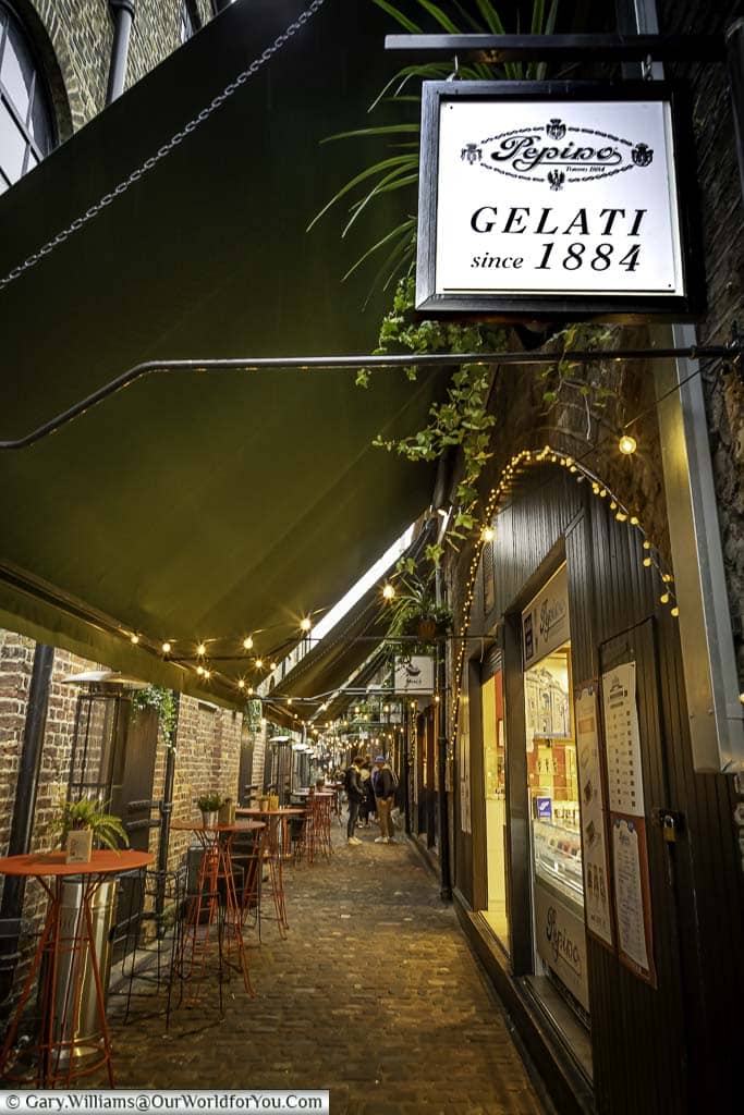A look Italian Alley in Camden Market lined with tables & stools on one side and Italian treats on the other. The first store is Gelati Pepino serving fine coffee and amazing gelato.