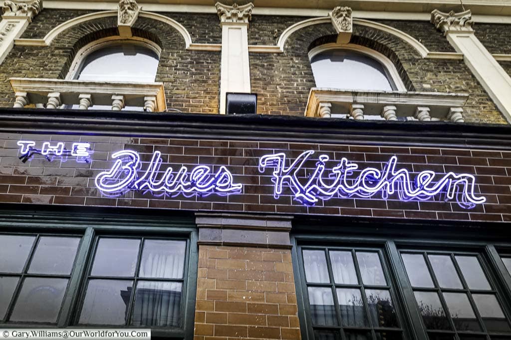 A close-up of the blue neon sign for 'The Blues Kitchen' on Camden high street.
