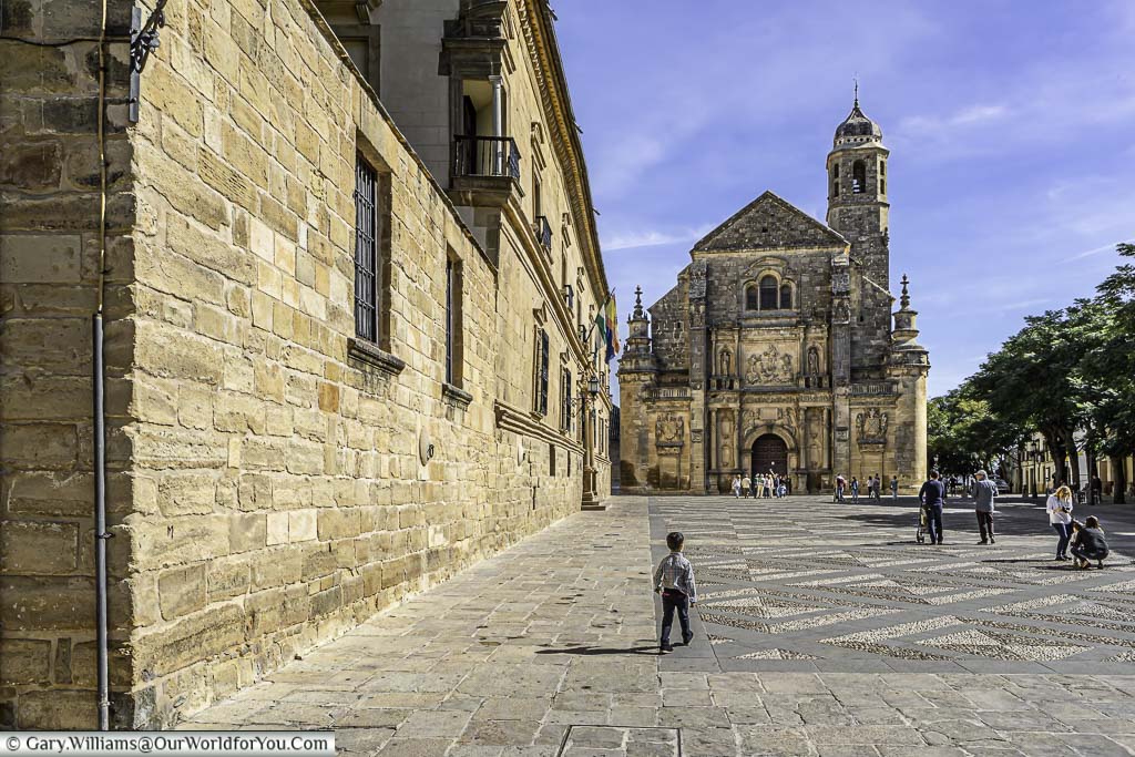 A small child walking across the courtyard in front of the Sacra Capilla del Salvador.