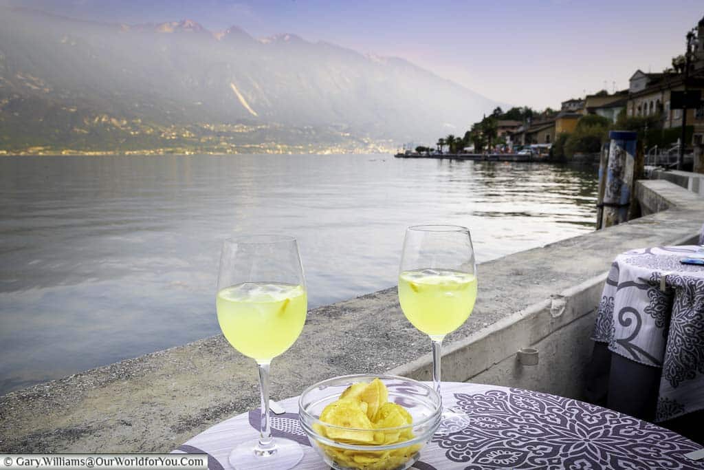 Two glasses of Limoncello Spritz at a bar table next to Lake Garda in Limone-sul- Garda, Italy