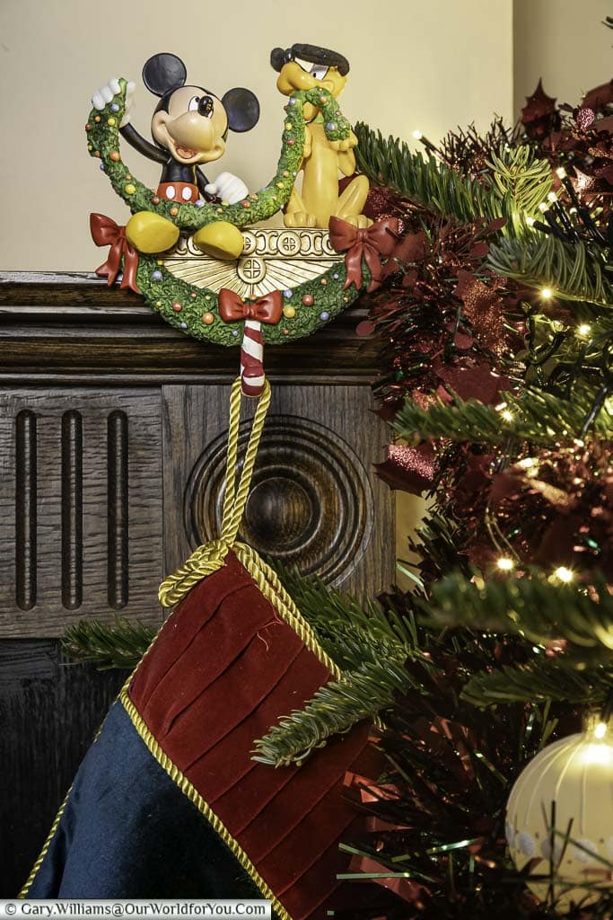 Our mickey mouse and pluto disney stocking holder, with a stocking attached placed on our mantlepiece over our fireplace