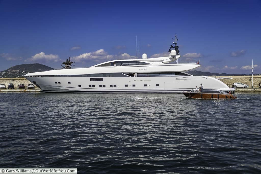 A wooden launch passing a superyacht moored up in saint tropez harbour in the south of france