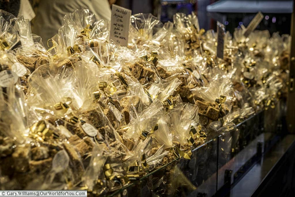 A closeup of gingerbread in small cellophane packets, tied with gold ribbons on a Christmas market stall.