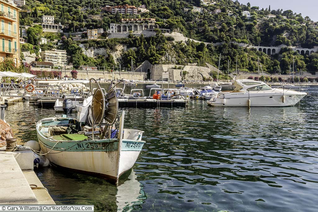 The harbour of Villefranche-sur-Mer, with a small fishing boat in the foreground and the hillside in the background.