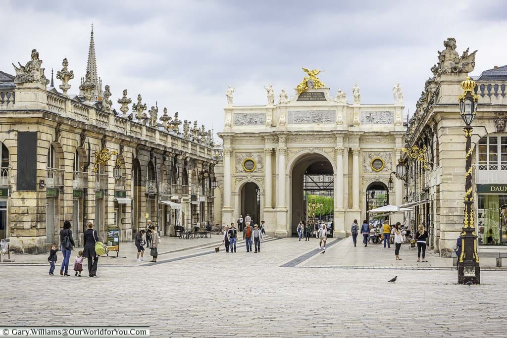 The arc héré, one entrance to the UNESCO place stanislas in nancy with the black and gold wrought iron lamp posts.