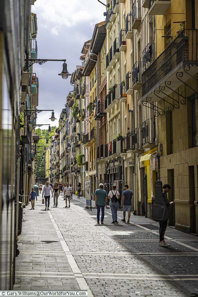 The cobbled lane of calle caldereria, lined on either side by colourful, historic, balconied, 5-storey buildings in the centre of pamplona in spain