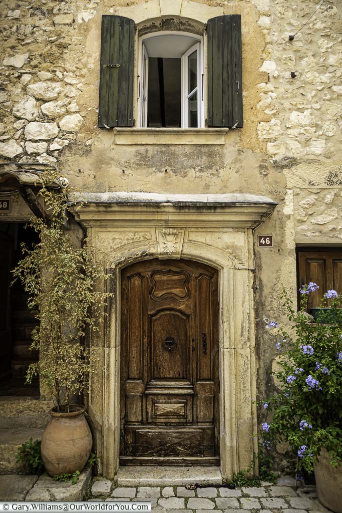 An ornate wooden door of number 46 set ain a stone building in Tourrettes sur Loup