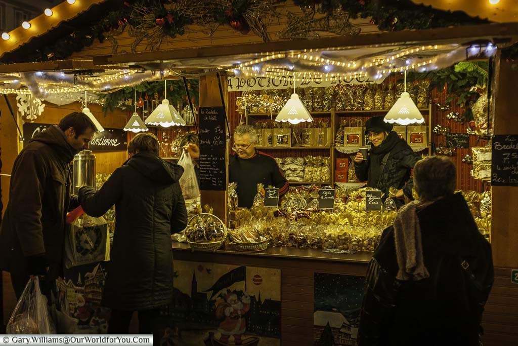 Customers at a stall in stasbourgs christmas market in the evening buying sweet treats for the festive period