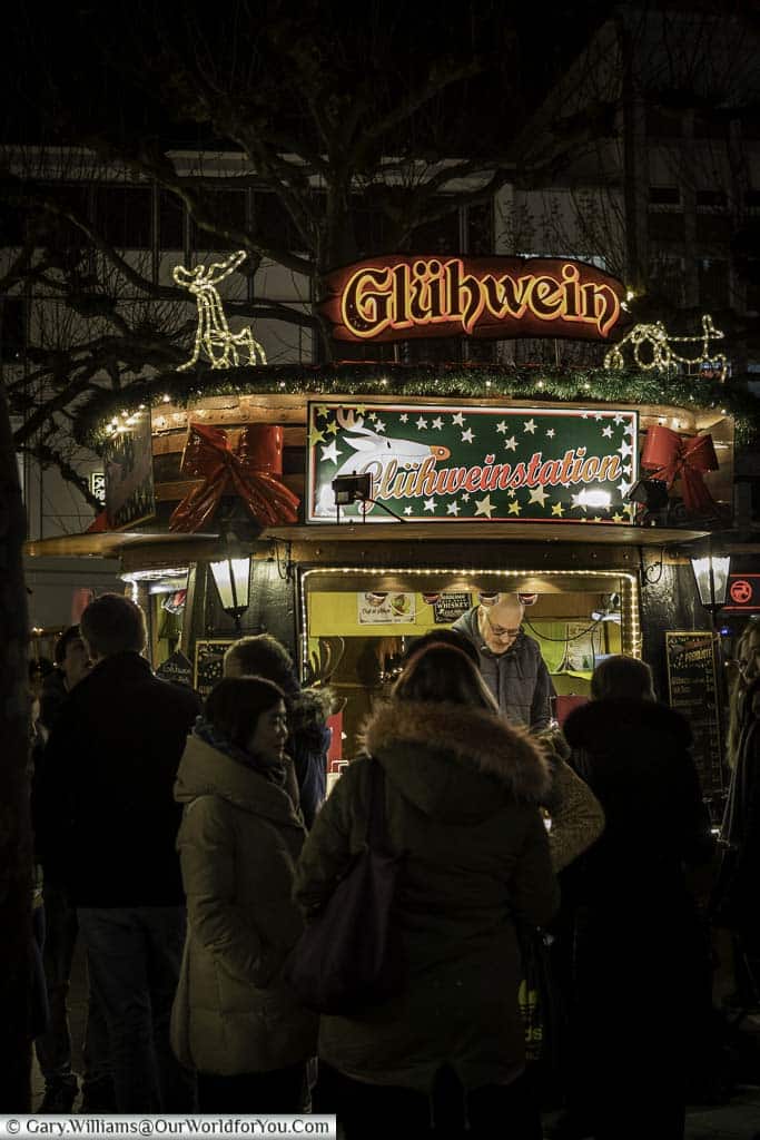 A group of people queuing at a Glühwein hut at the Hauptwach Christmas Market.