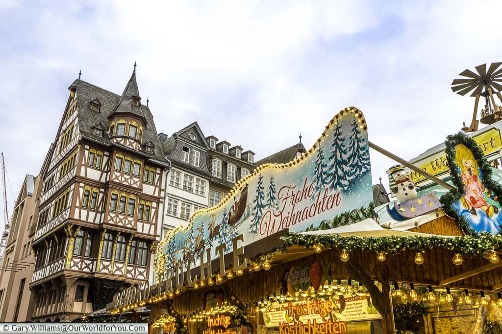 The ornate roof of a Christmas market stall in Römerberg in front of a half-timber building.