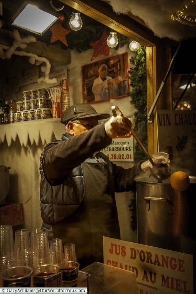 A mature man ladling out hot spiced orange juice at a stall on the Strasbourg Christmas markets in 2008.