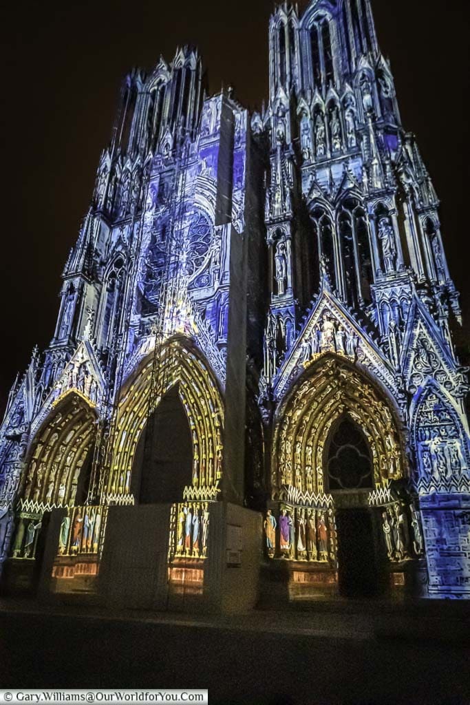 The entrance to Reims Cathedral at night, with a projected art installation depicting the history of this French City