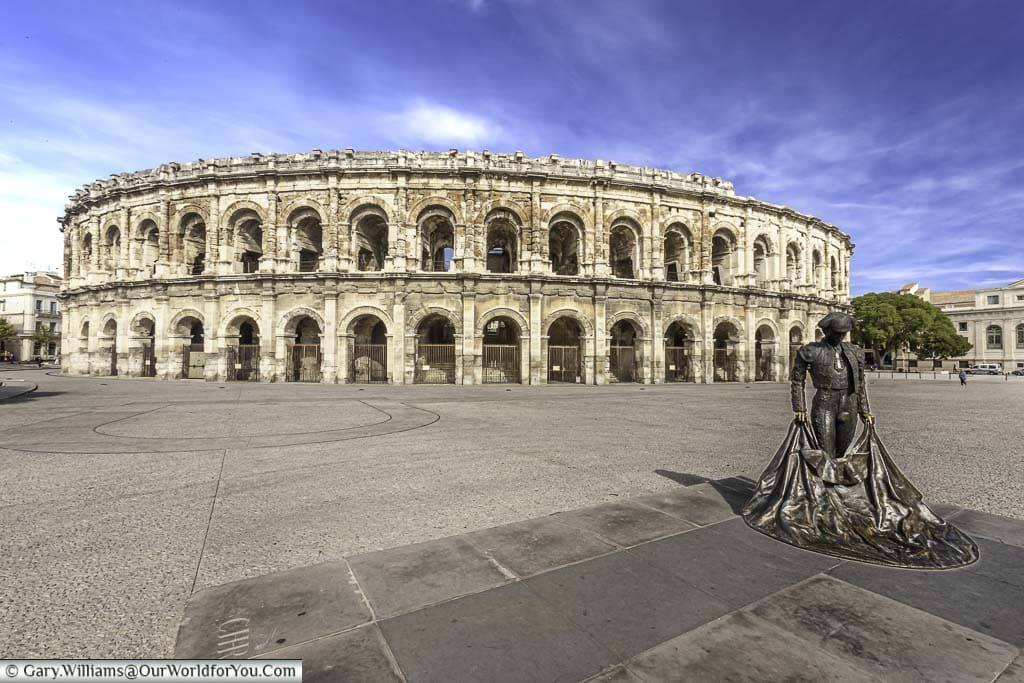 The brass statue of a bullfighter in front of the complete, two-storey, Roman arena in Nîmes.
