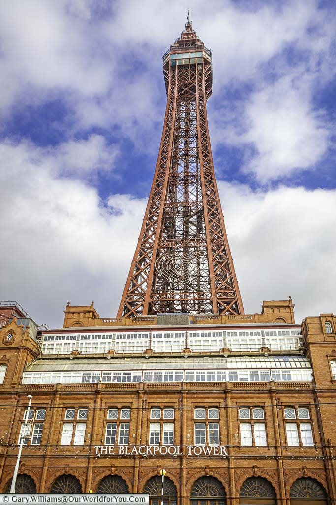 Looking up at the Blackpool Tower with its red brick base, and red wrought iron framework.