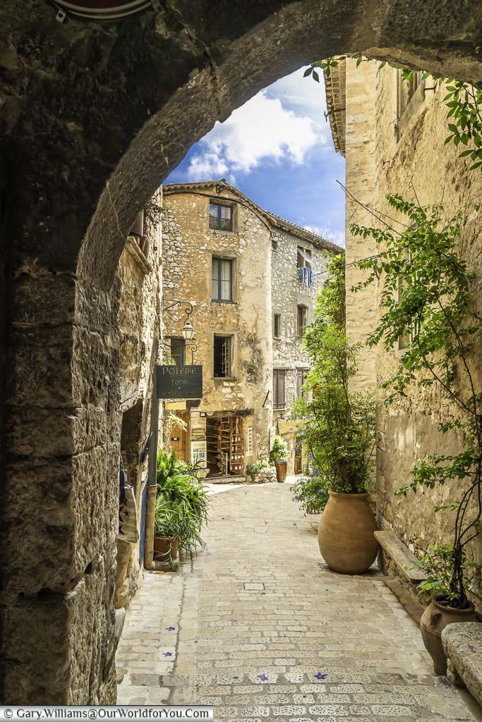 A view through an archway to a narrow cobbled lane between rough stone provencal buildings in tourrettes sur loup in the provence region of france