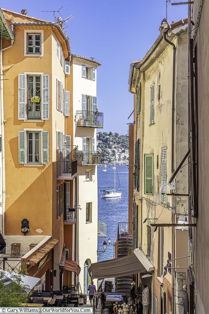 Looking down through the narrow lanes of Villefranche-sur-Mer between the brightly coloured buildings to the blue waters of the bay