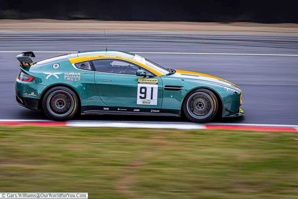 an aston martin vantage gt4 rounding druids hairpin at the brands hatch motor racing circuit in kent, england