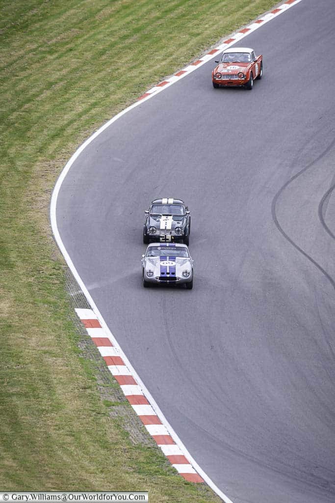 Three classic sports cars on the run down to graham hill bend at brands hatch motor racing circuit