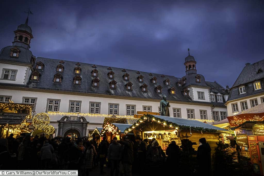 crowds gathering at the christmas market stalls in koblenz's jesuitenplatz looking up at the giant advent calendar in the city's rathaus
