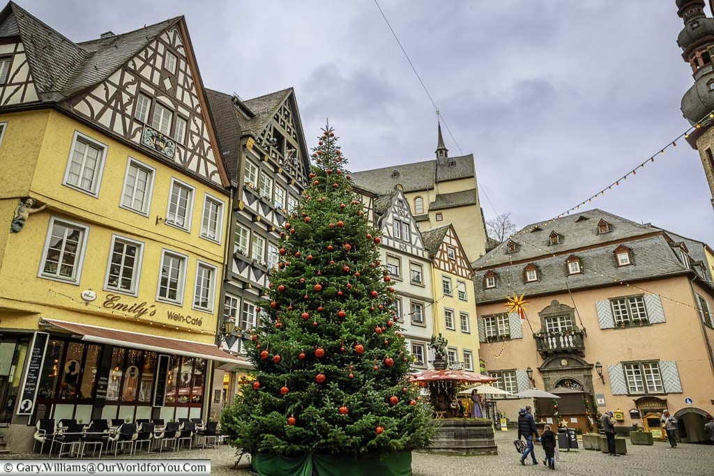 a giant christmas tree, decorated with red baubles, in the markplatz square, lined with historic german buildings in the centre of the traditional german town of cochem, on the banks of the moselle ri