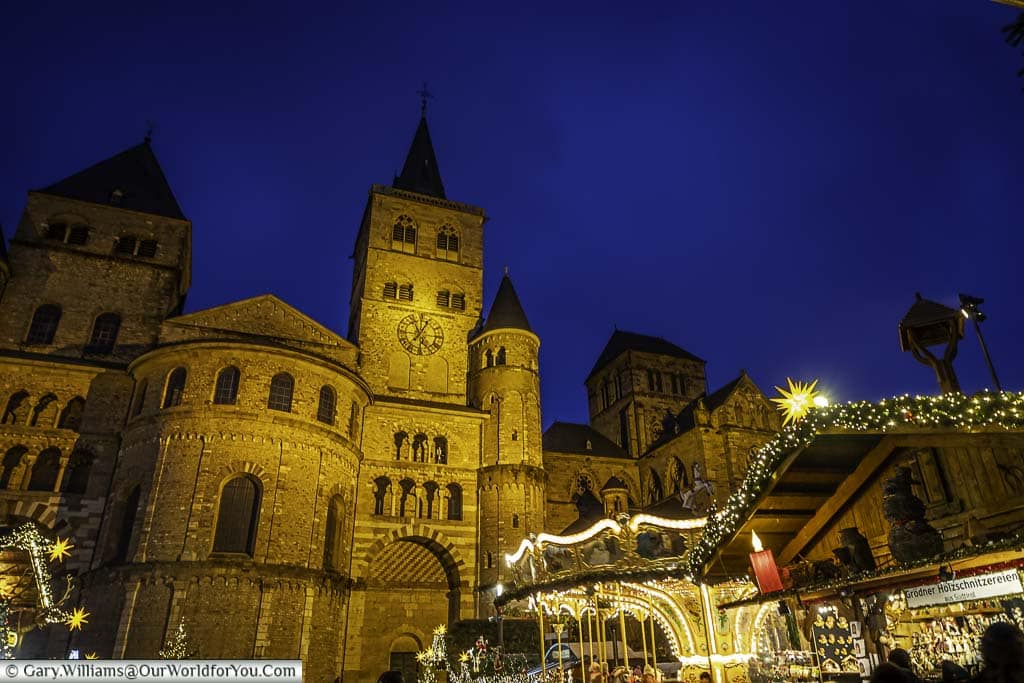 twinkling christmas market stalls around the base of trier's cathedral at dusk